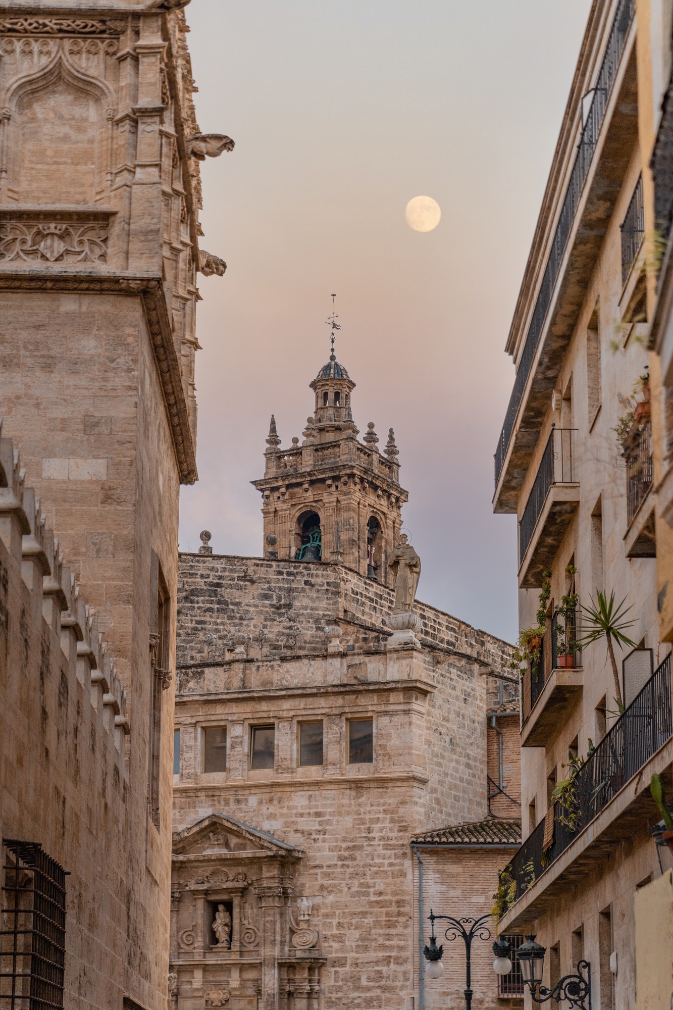 View of the bell tower of a parish in the old town of Valencia city at dusk with the moon rising.